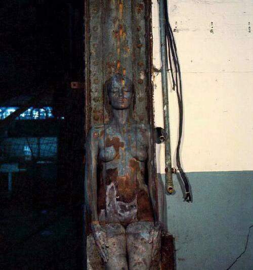 Painted woman in front of front of corroded hanger